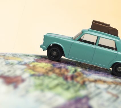 Close-up of a toy car with luggage on holiday sitting on a globe